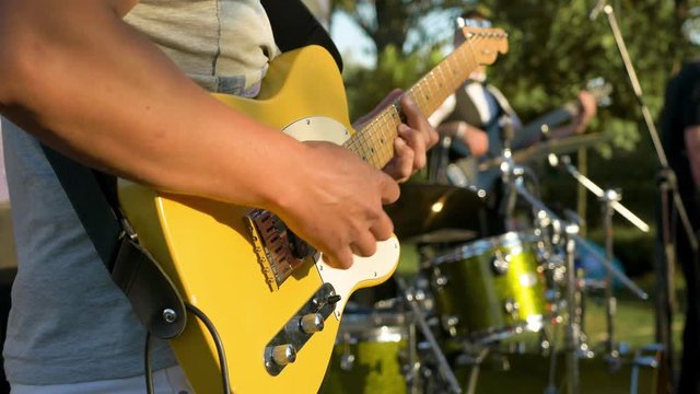 close-up guy playing a yellow guitar standing on the stage