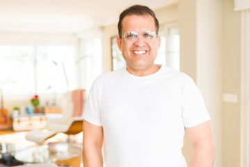 Middle age man wearing glasses smiling to the camera at home