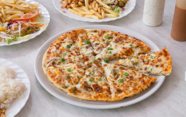 Delicious fresh pizza served in portions on the plate on the marble table