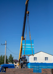 Crane unloads bricks at a house construction