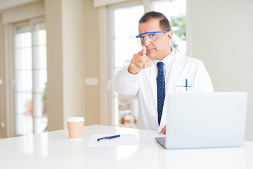 Fototapeta premium Middle age scientist man wearing professional glasses working using laptop pointing with finger to the camera and to you, hand sign, positive and confident gesture from the front