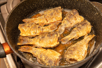 Fried fish in a pan in the kitchen