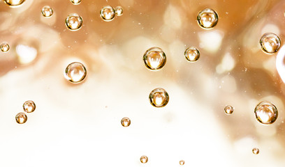 Bubbles of air on the smooth surface of golden water as an abstract background
