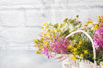 bouquet of beautiful wildflowers in a basket on a gray background with copy space.