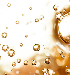 Bubbles of air on the smooth surface of golden water as an abstract background