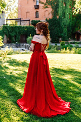 Fototapeta premium Redhead woman in red dress near the castle