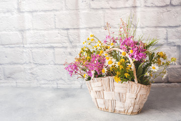 bouquet of beautiful wildflowers in a basket on a gray background with copy space.