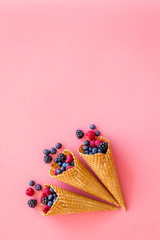 Summer breakfast with fresh berries in waffle cones on pink background top view mockup