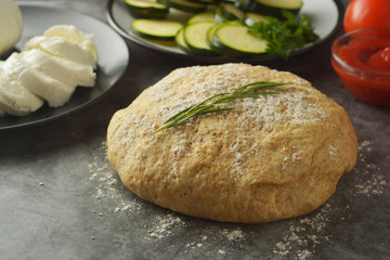 Composition with raw dought and fresh ingredients for pizza isolated on dark background. Copy space. Flat lay food ingredients.