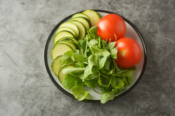 Fresh vegetables in a plate - salad mix, tomatoes and zuchinni. Healthy food concept, lose weight.