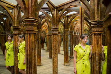 Young woman in yellow dress in big mirror room.