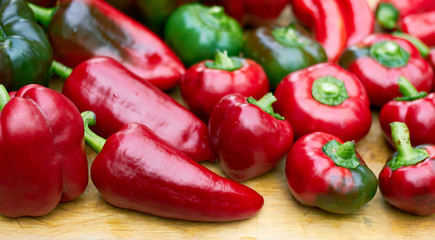 Sweet red pepper assorted on the wooden cutting board, soft focus, closeup, background texture for your design, eco food and agriculture harvest concept