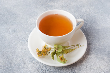 Cup of green tea and flowers linden on grey background. Copy space.