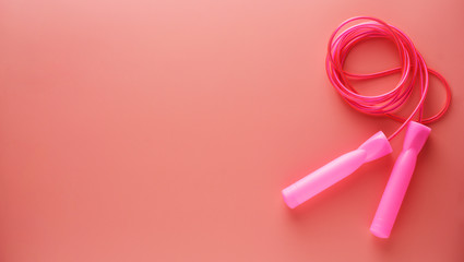 Pink jumping rope or skipping rope isolated on pink background. Sports, fitness, cardio, healthy workout concept. Banner.