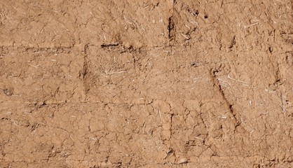 A wall of adobe blocks interspersed with straw