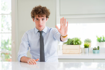 Young business man wearing a tie doing stop sing with palm of the hand. Warning expression with...