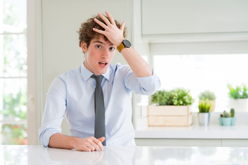 Young business man wearing a tie surprised with hand on head for mistake, remember error. Forgot,...