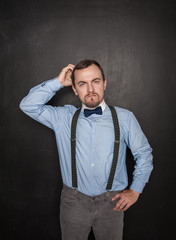 Handsome business man scratching his head on blackboard
