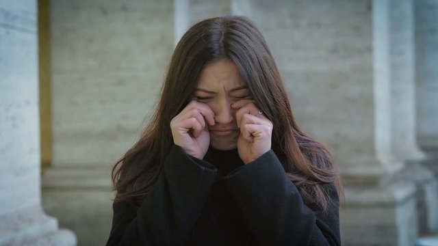 funny pretty woman playing the gesture of crying in the street