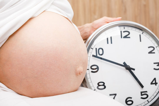 Pregnant Woman With Clock - Final Weeks Of Pregnancy Concept