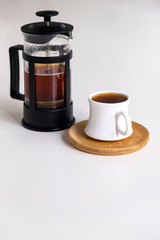Cup of coffee made with French press is ready to serve, white background.