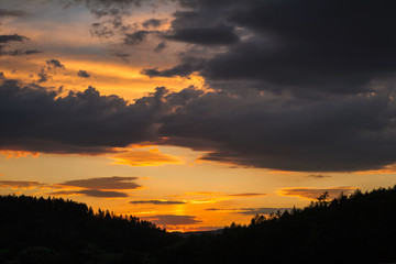 Amazing sunset clouds on field with forest and sky. Czech landscape