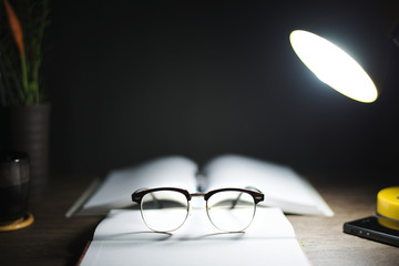 Reading table at night, With books, glasses, lamps, Focus on glasses, Education concept.