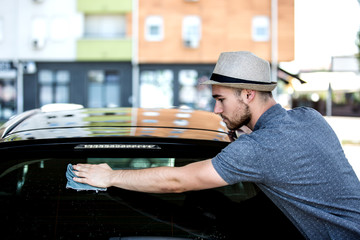 Young man washing his car in car wash