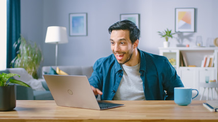 Shot of a Happy and Excited Handsome Man Working on a Laptop. Freelances Working from His Living...