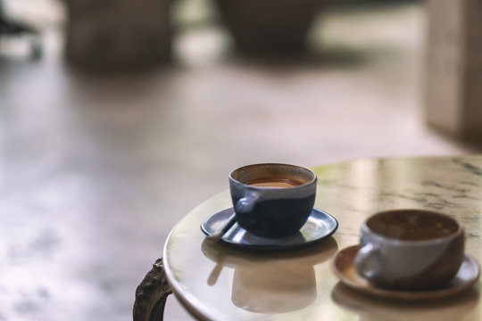 Closeup image of two cups of hot coffee on marble table in cafe