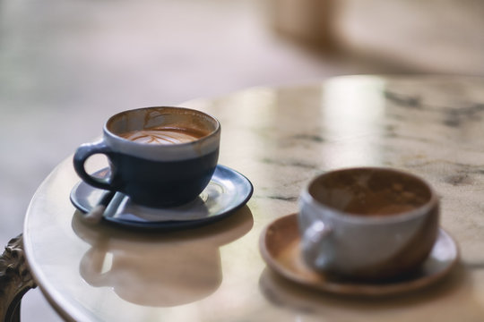 Closeup image of two cups of hot coffee on marble table in cafe