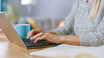 Close-up Shot of a Woman with Beautiful Nails Typing on a Laptop while Sitting at Her Desk at Home.