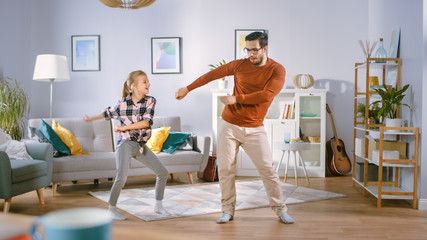 Happy Little Girl Dances with Young Father in the Middle of the Living Room. Happy Family Time,...