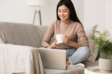 Happy Girl Relaxing on Comfortable Couch and Using Laptop