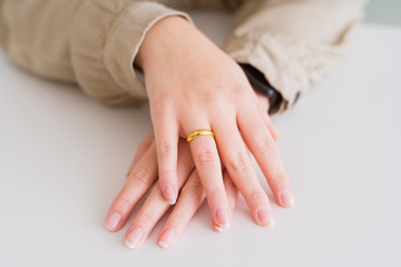 Close up of woman hands showing golden alliance with hands on each other over white table