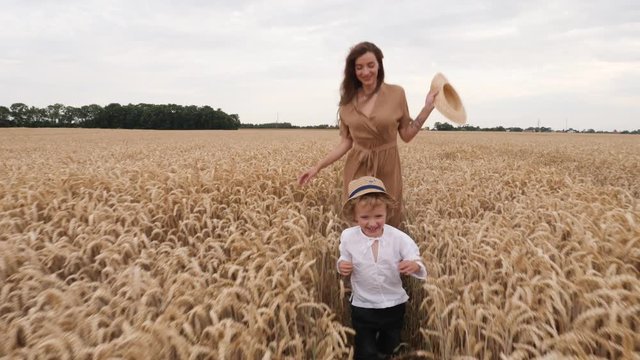 Happy family slow motion running young beautiful mother and child son in a wheat field countryside nature