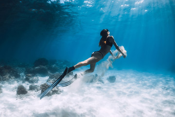 Obraz na płótnie Canvas Woman freediver swim underwater over sandy bottom with sand in hands
