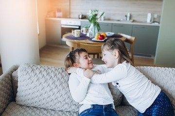 Portrait of little caucasian adorable girls playing together in cozy bedroom smiling and relaxing in scandinavian design style. Happiness, leisure, children lifestyle, childhood, education concept