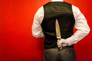 Portrait of Butler or Waiter Holding Knife Behind His Back. I Quit. Concept of Disloyalty. Dark...