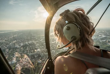 Foto op Plexiglas Portrait of beautiful blonde women enjoying helicopter flight. She is amazed by cityscape. © MexChriss