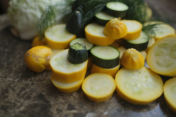 Zucchini, sliced rings, and other vegetables, surrounded with cucumbers, cabbage and dill.