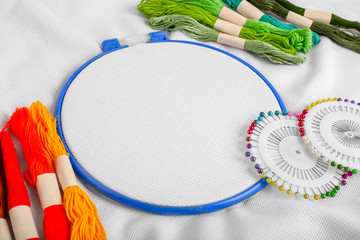Tools for cross stitch. A hoop for embroidery and canvas on white canvas background. Mockup for hobby. Embroidery process with mouline thread.