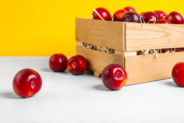 Fresh cherry plums in wooden box on yellow colorful background . Vegetarianism. Close up