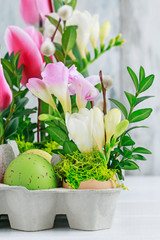 Easter floral decoration with colorful eggs, tulips, freesias and buxus.