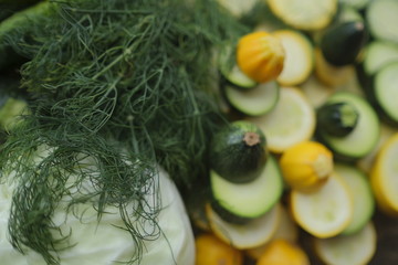 Zucchini, sliced rings, and other vegetables, surrounded with cucumbers, cabbage and dill.
