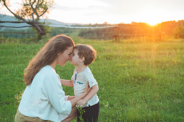 Happy mother and son on nature on sunset. Family, children and happy people concept. Mothers day