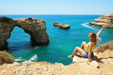 Young beautiful woman enjoying the panoramic top view of rocky beaches with cliffs somwhere,...