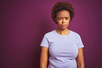 Obraz premium Young beautiful african american woman with afro hair over isolated purple background skeptic and nervous, frowning upset because of problem. Negative person.