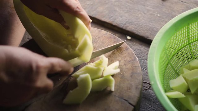 Old lady using knife to cut a winter melon to pieces. Ingredient for cooking