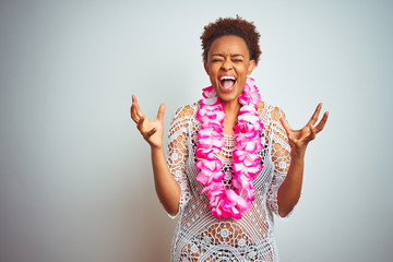 Young african american woman with afro hair wearing flower hawaiian lei over isolated background...